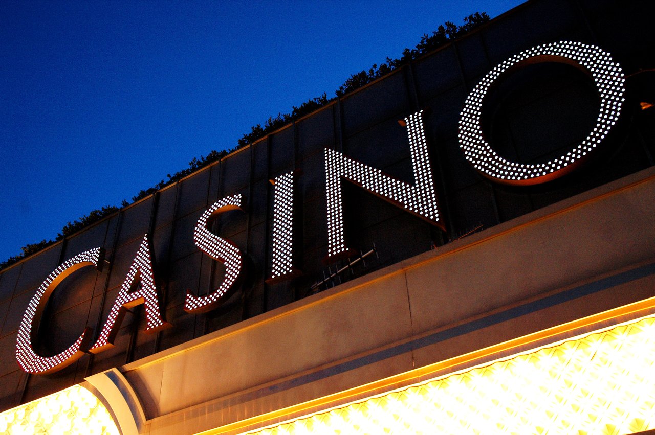 A brightly lit casino sign at night, with glowing letters against a dark blue sky.