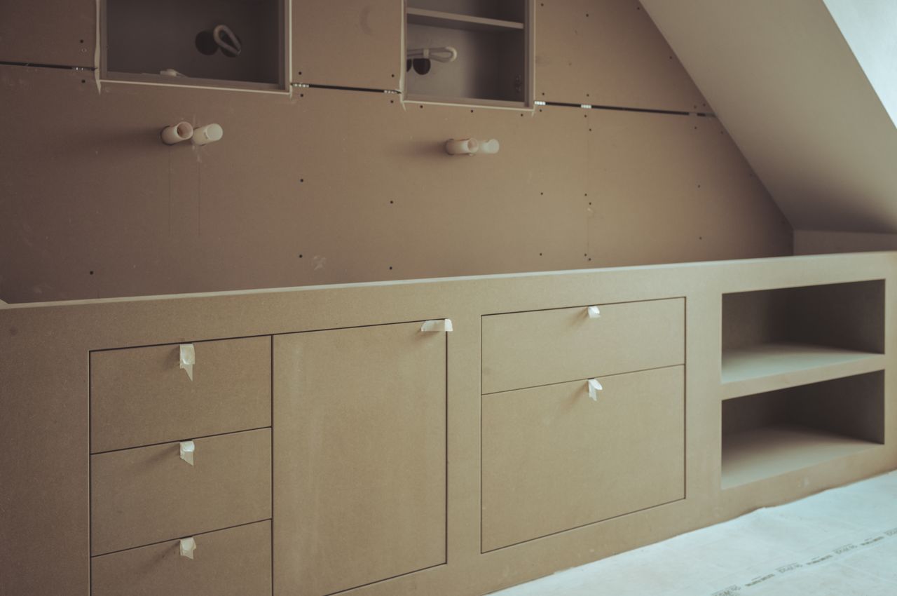 A custom double sink bathroom vanity under construction, made of unfinished wood. Faucets and tabletop are yet to be installed.