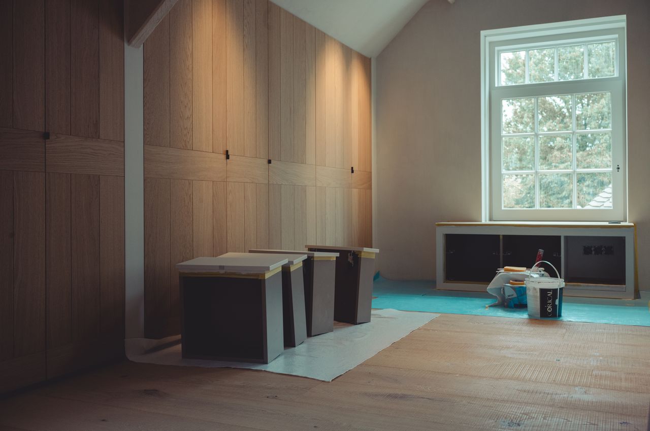 Built-in cabinets made out of oak with newly-painted drawers drying on the floor in front of them.