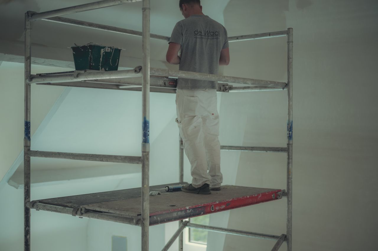 A painter on scaffolding preparing to paint the ceiling.