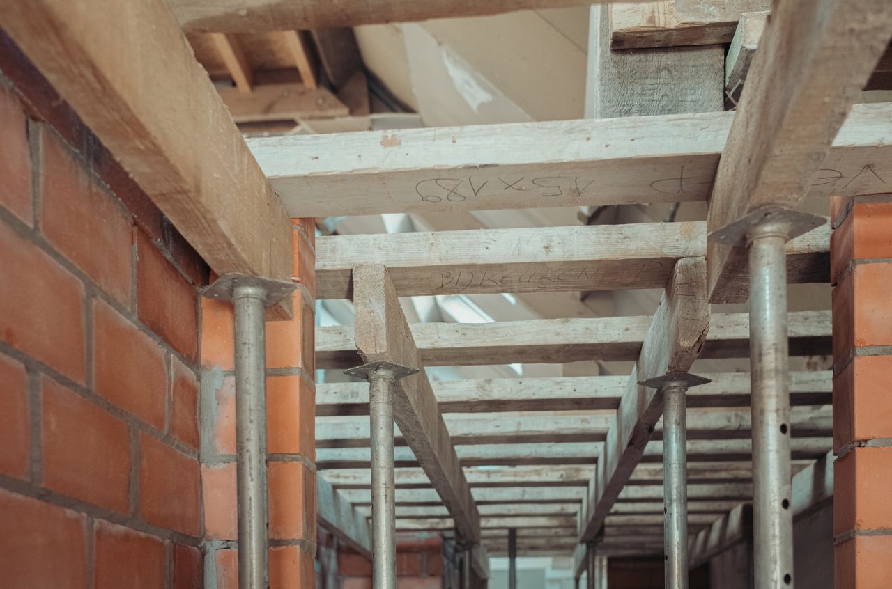 Wooden and metal supports in place for pouring a concrete floor in a brick building under construction.