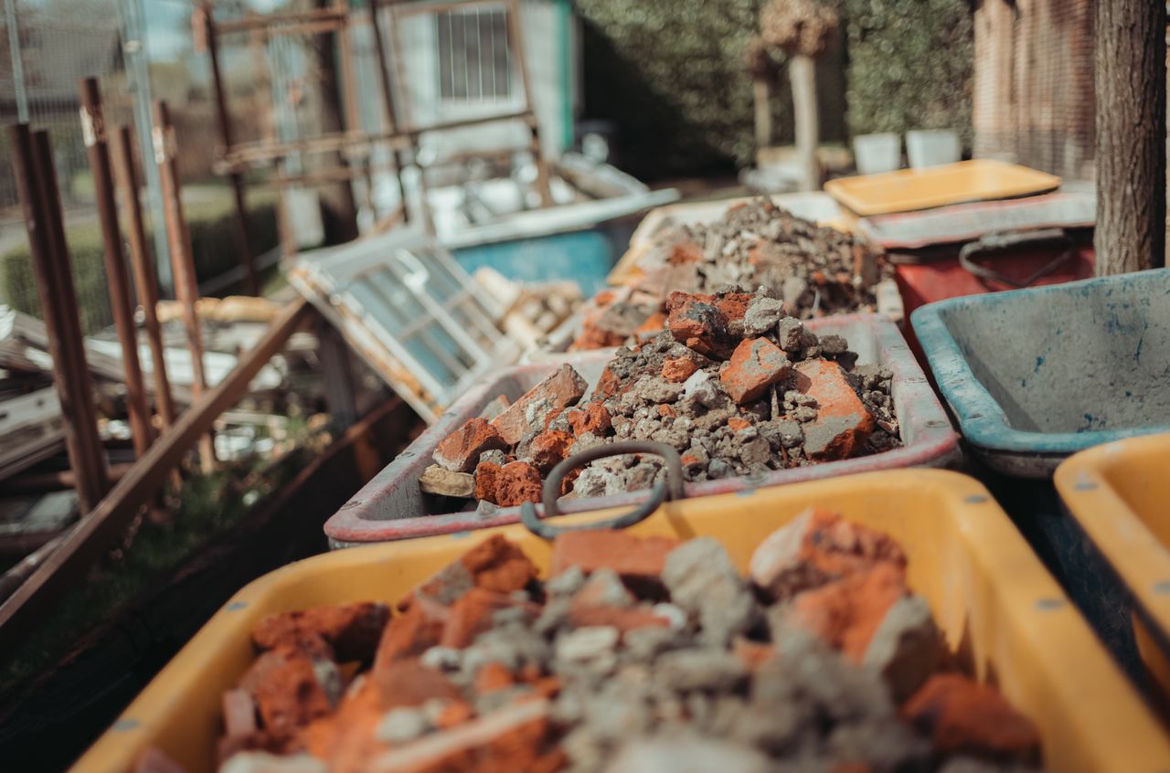 Several wheelbarrows filled with broken bricks and rubble from a demolition project, lined up outdoors.