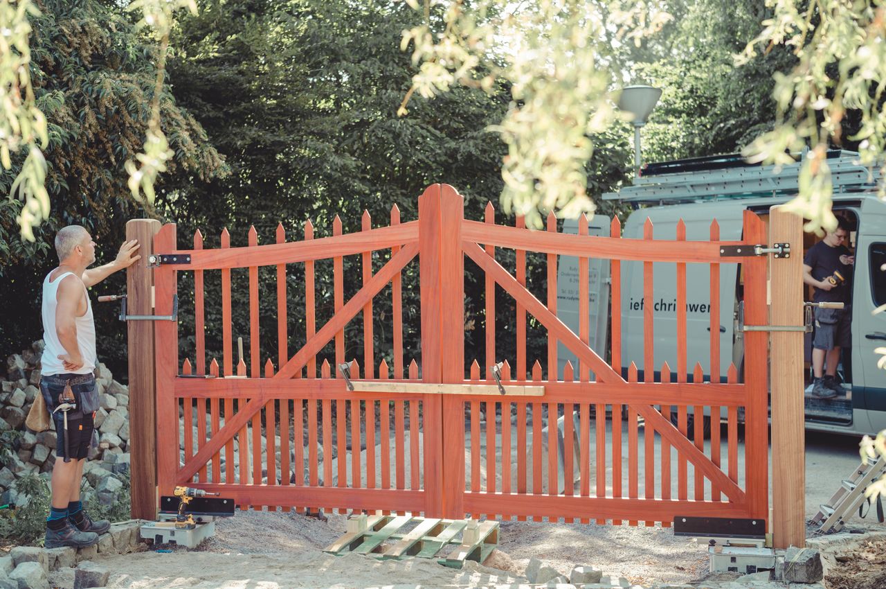 A person installing a gate for the driveway.