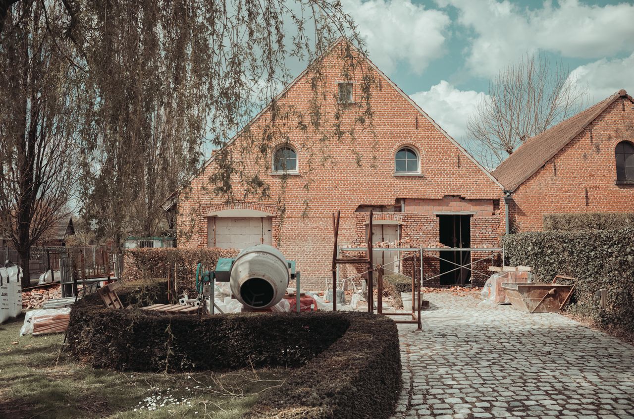 A brick building under renovation, with a garage door replaced by a window and door.
