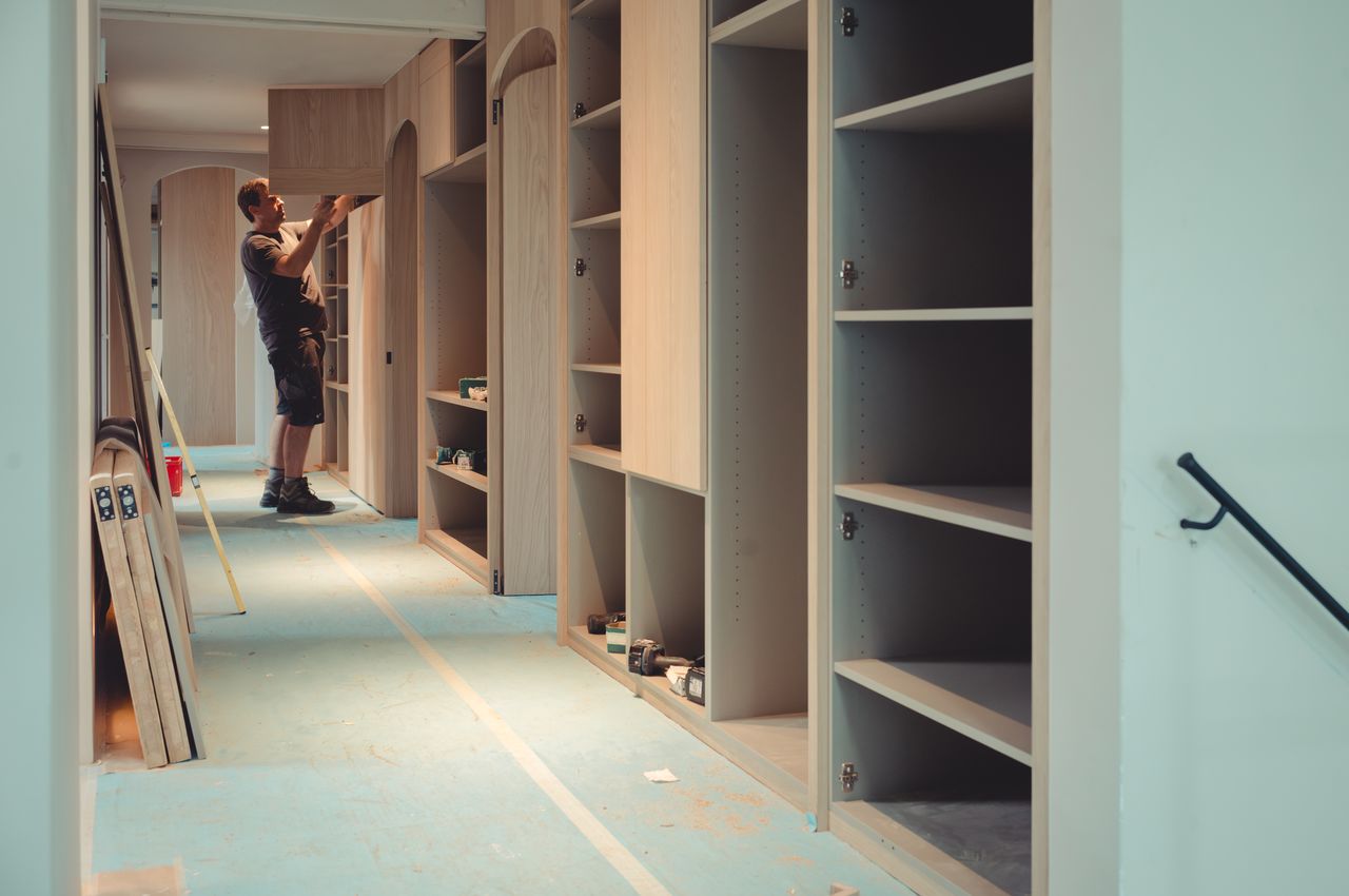 A person is putting doors on cabinets.