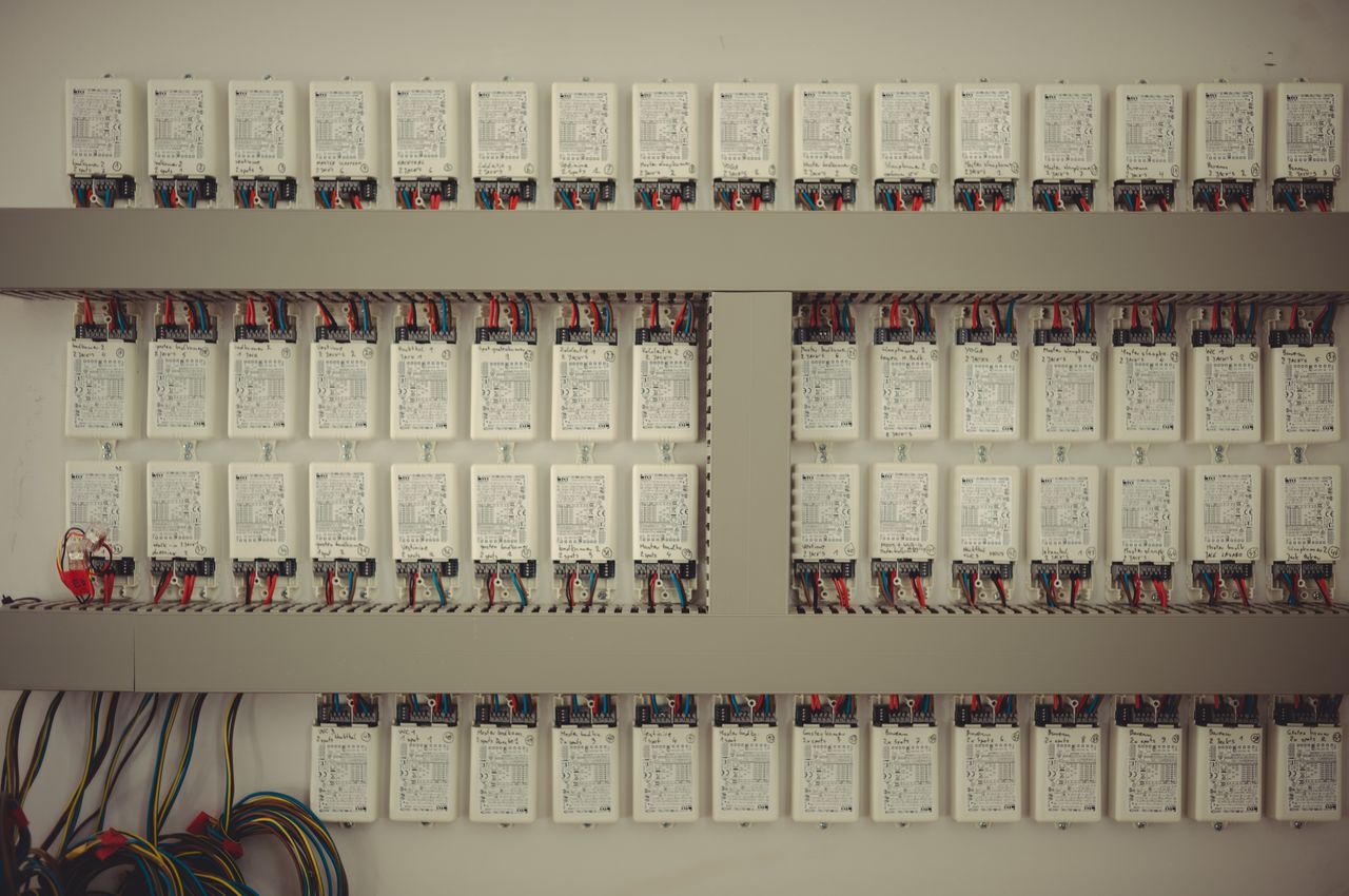 A wall with rows of LED drivers. Every LED driver is a rectangle-shaped box with black text printed on it.
