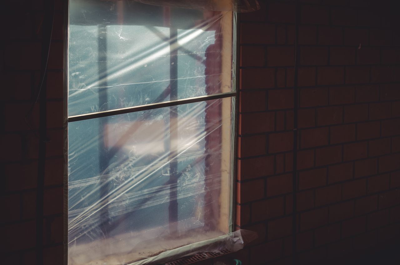 A window covered with plastic sheeting, temporarily sealed while waiting for the actual windows to be installed.