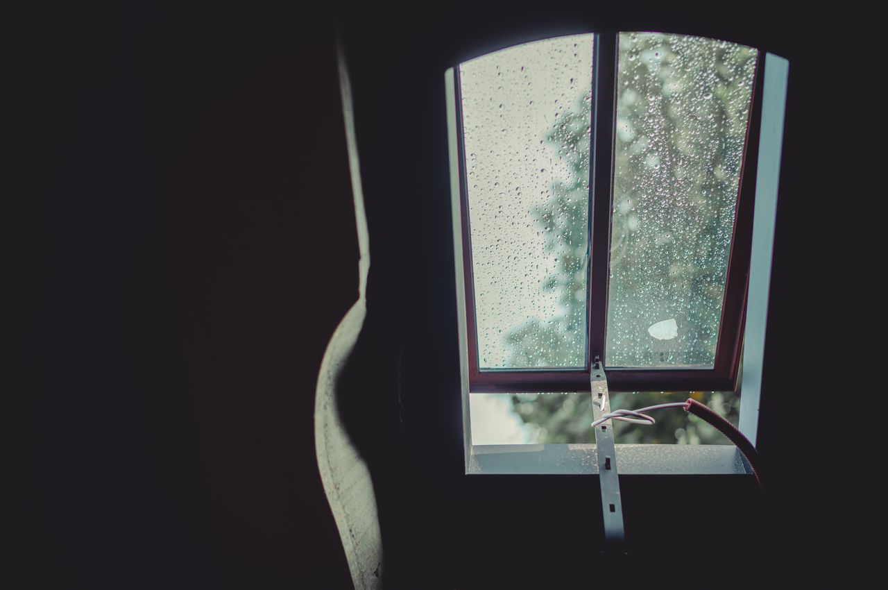 A wrought iron skylight with raindrops on the glass, partially open, replacing a modern Velux window.