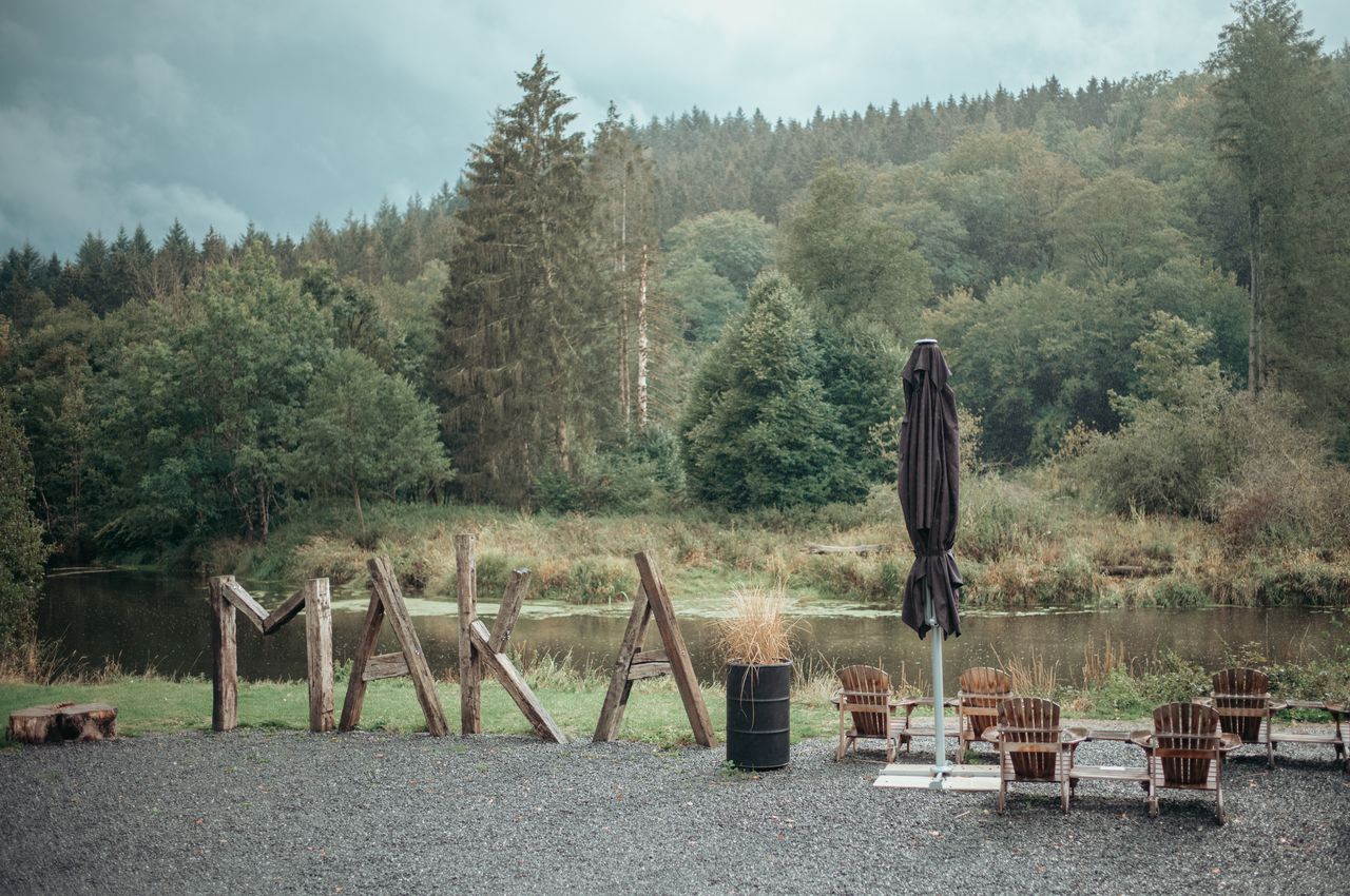 The word 'Maka' spelled with large logs, standing next to a river.