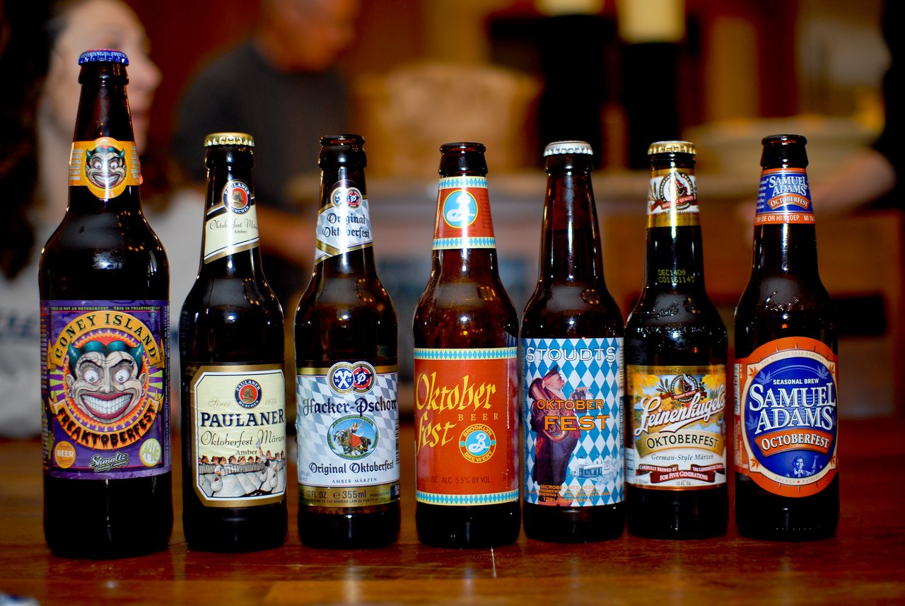 A row of seven Oktoberfest beer bottles displayed on a table for a beer tasting event.