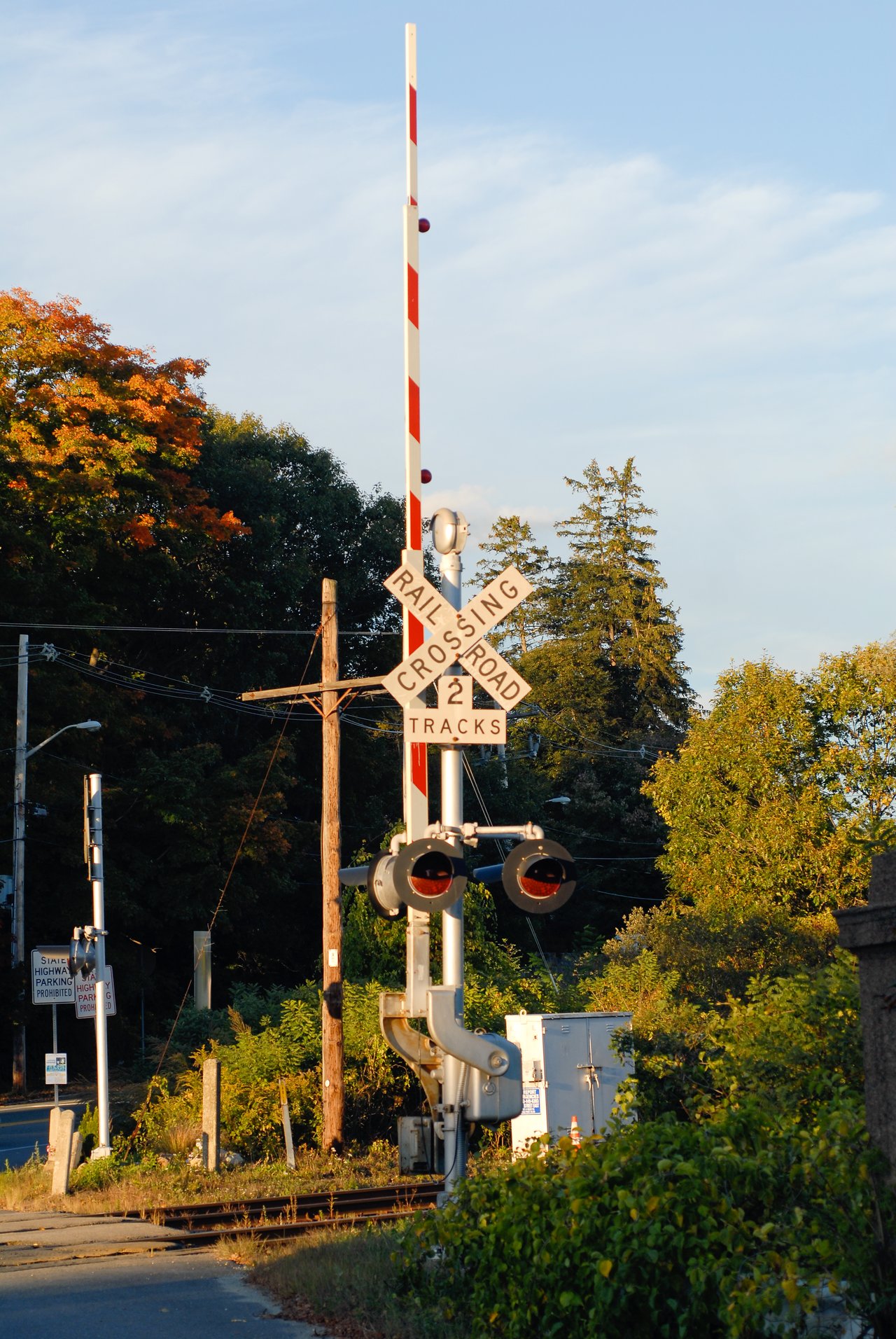 A railroad crossing with warning lights, a raised barrier, and a sign indicating two tracks.