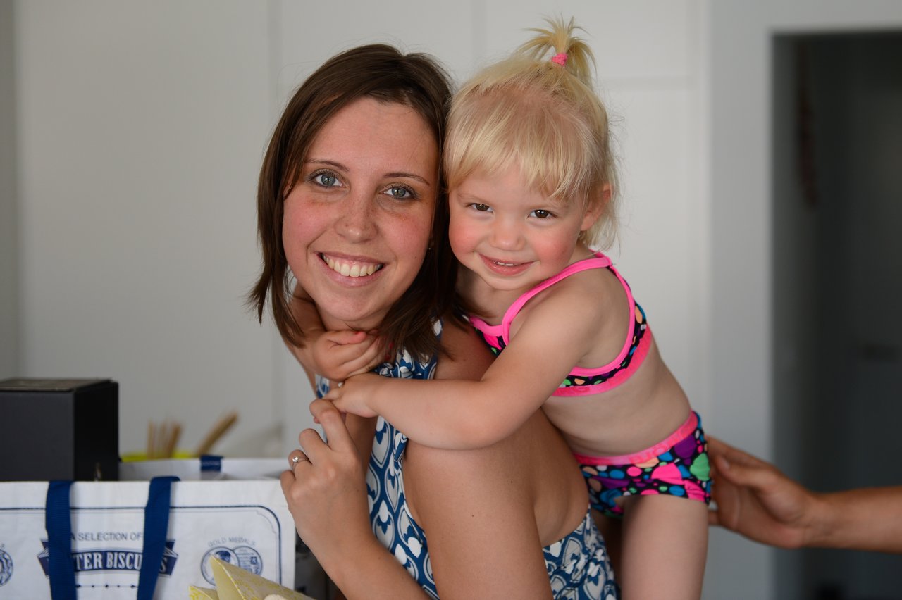 A woman smiles while carrying a young child on her back.