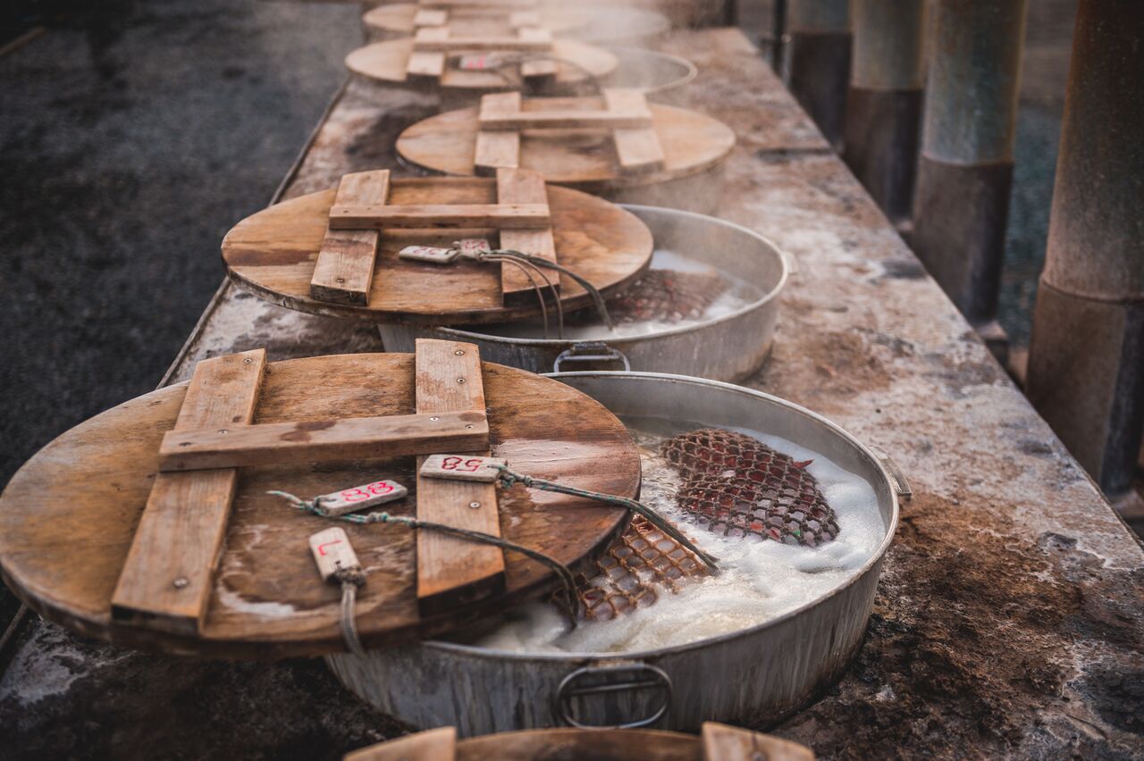 Large metal pots with wooden lids in which lobsters are boiled