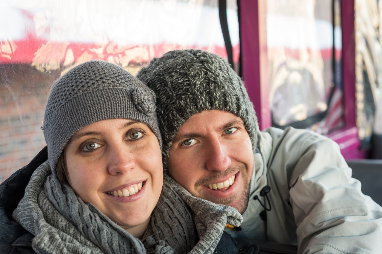A smiling couple in warm clothing sits close together on a Boston Duck Tour vehicle.