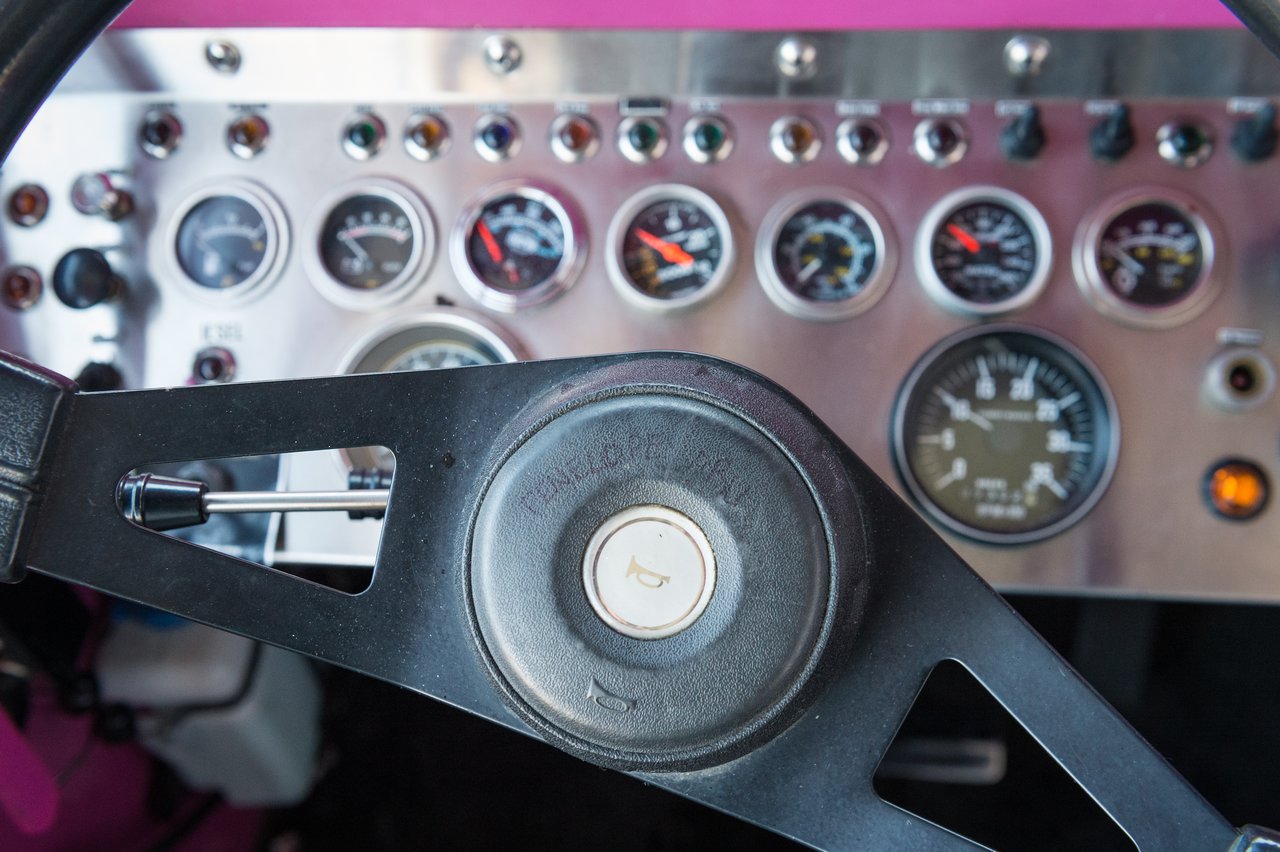Close-up of a vehicle's steering wheel and dashboard with multiple gauges and switches.