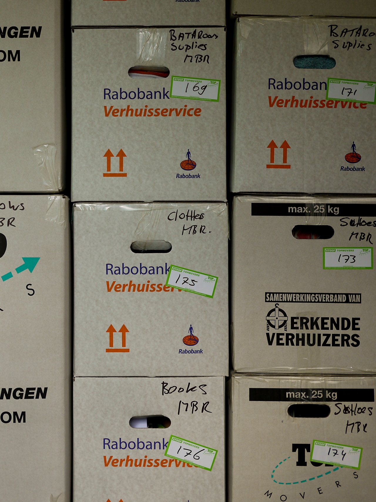 Stacked moving boxes labeled with contents like clothes, books, and bathroom supplies, marked with numbers for organization.