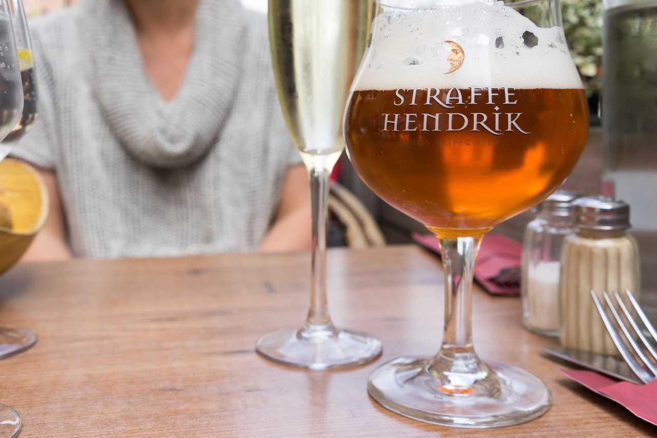 A glass of beer and a glass of champagne on a wooden table at a restaurant.