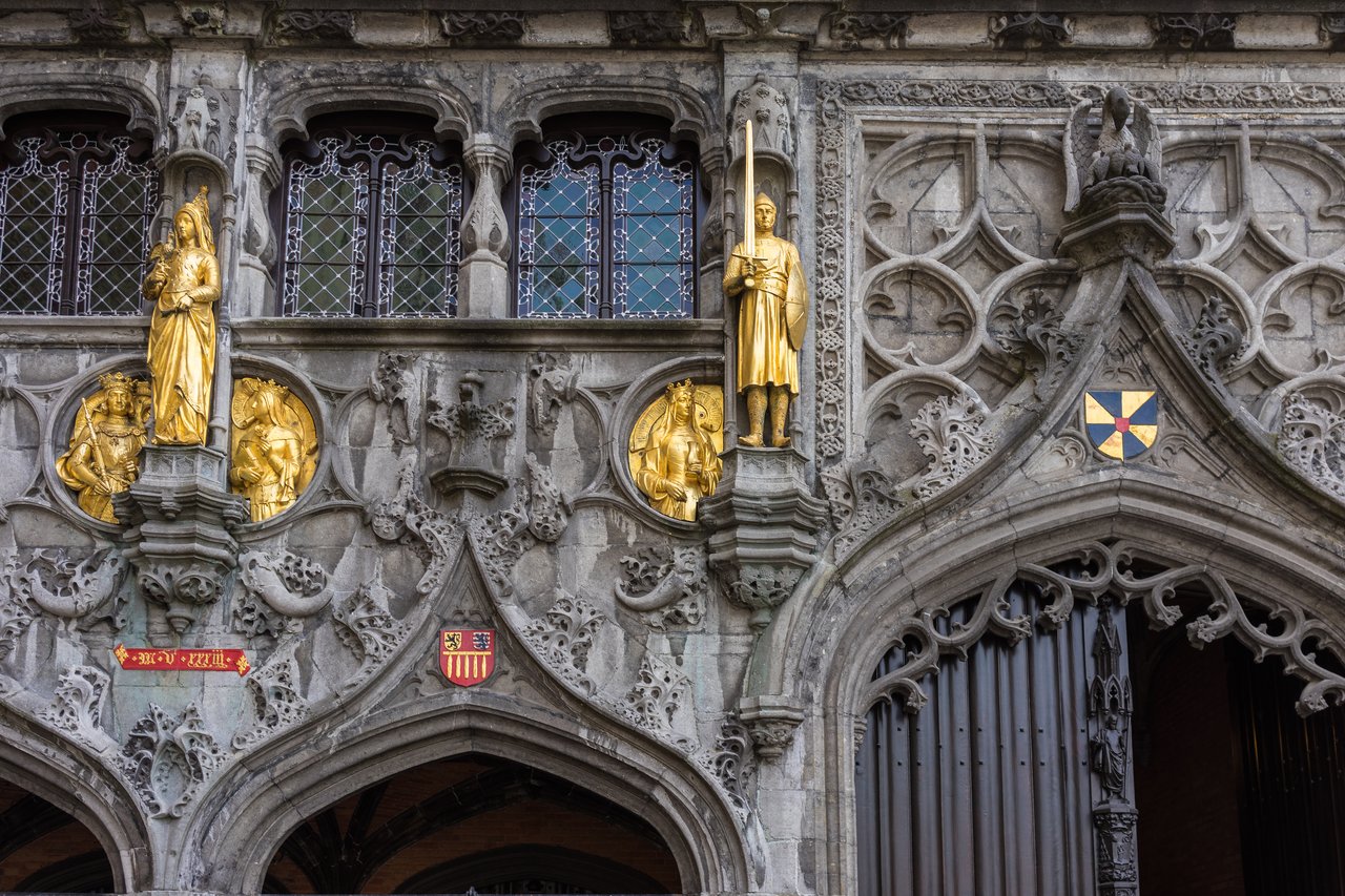Close-up of the Basilica of the Holy Blood's ornate facade, featuring golden statues and intricate stone carvings.