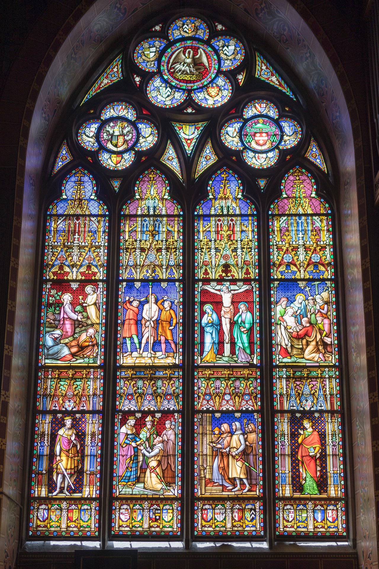 Stained glass window in the Basilica of the Holy Blood depicting biblical scenes, including the crucifixion of Jesus.