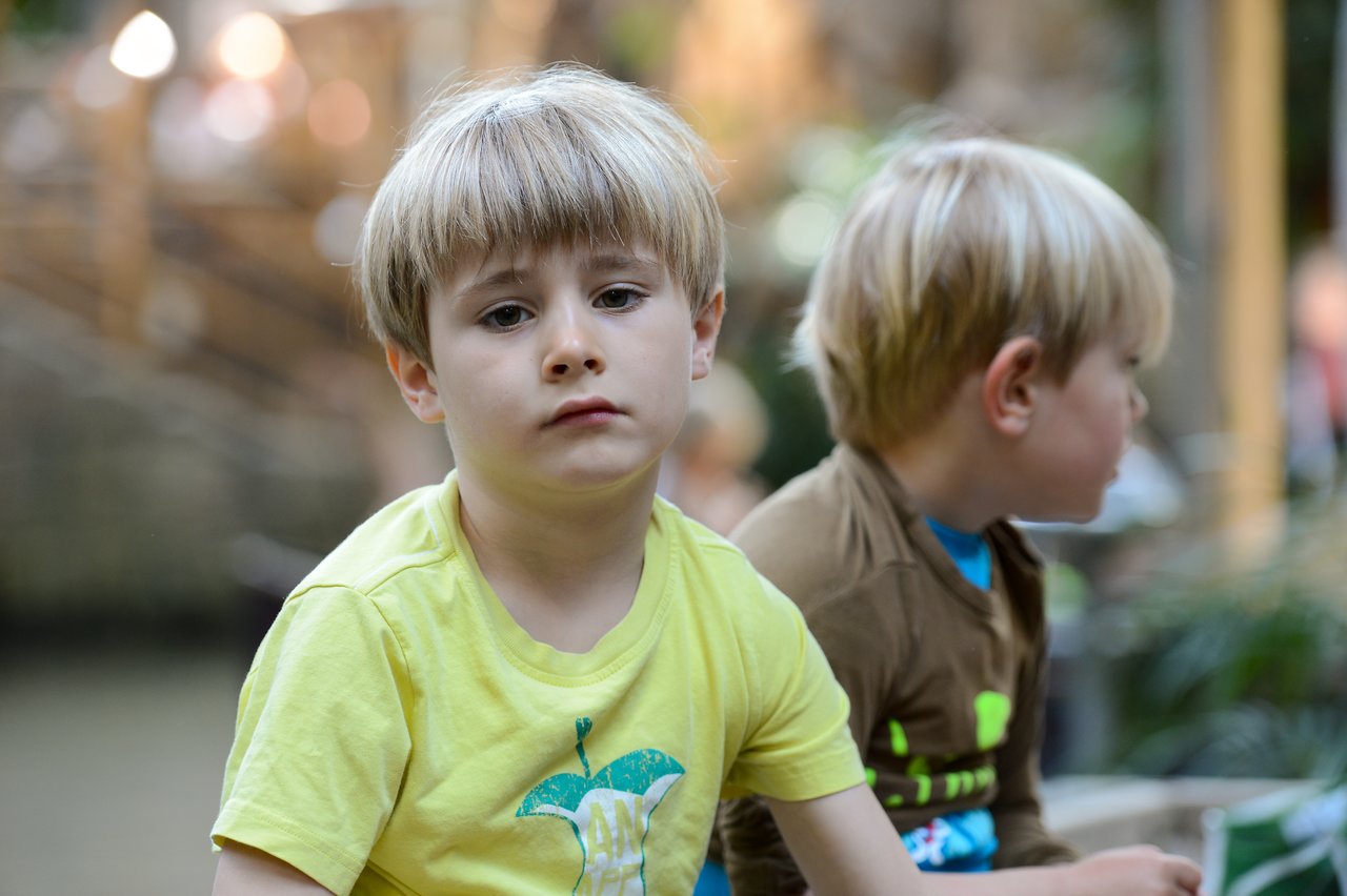 Two young boys with blonde hair sit together.