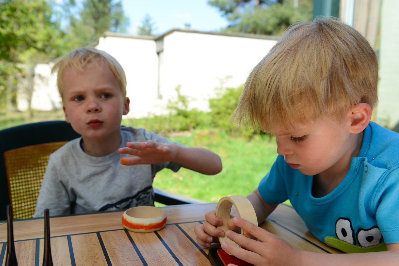 Two young boys sit at an outdoor table.