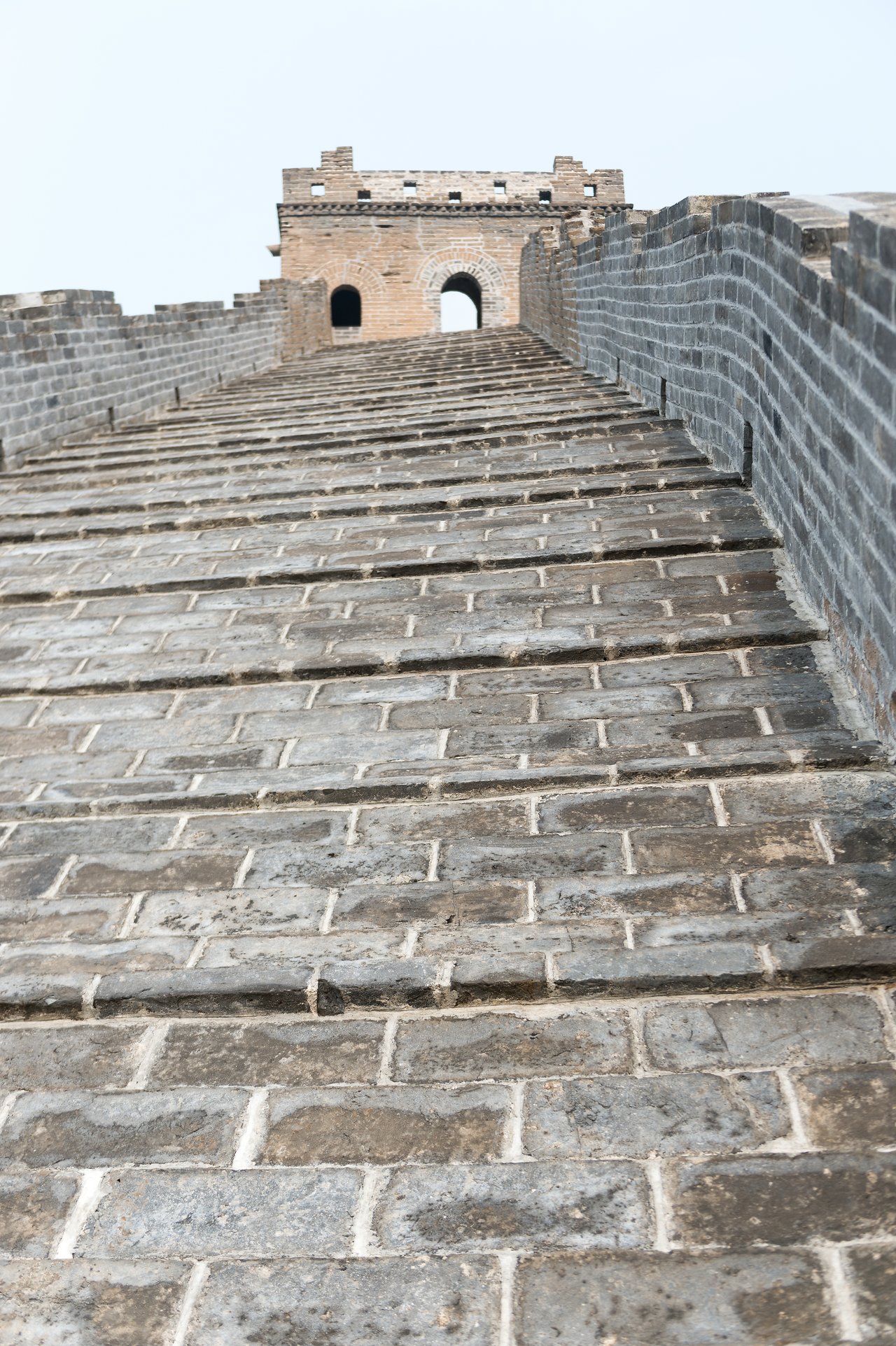 A steep stone pathway leads up to a watchtower on the Great Wall of China.