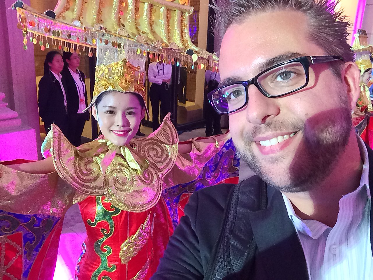 A man takes a selfie with a performer in a colorful traditional Chinese costume at the World Economic Forum event.