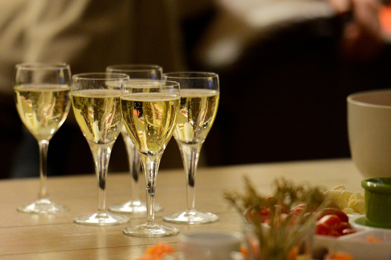 Five glasses of champagne on a table, with food and decorations in the foreground.