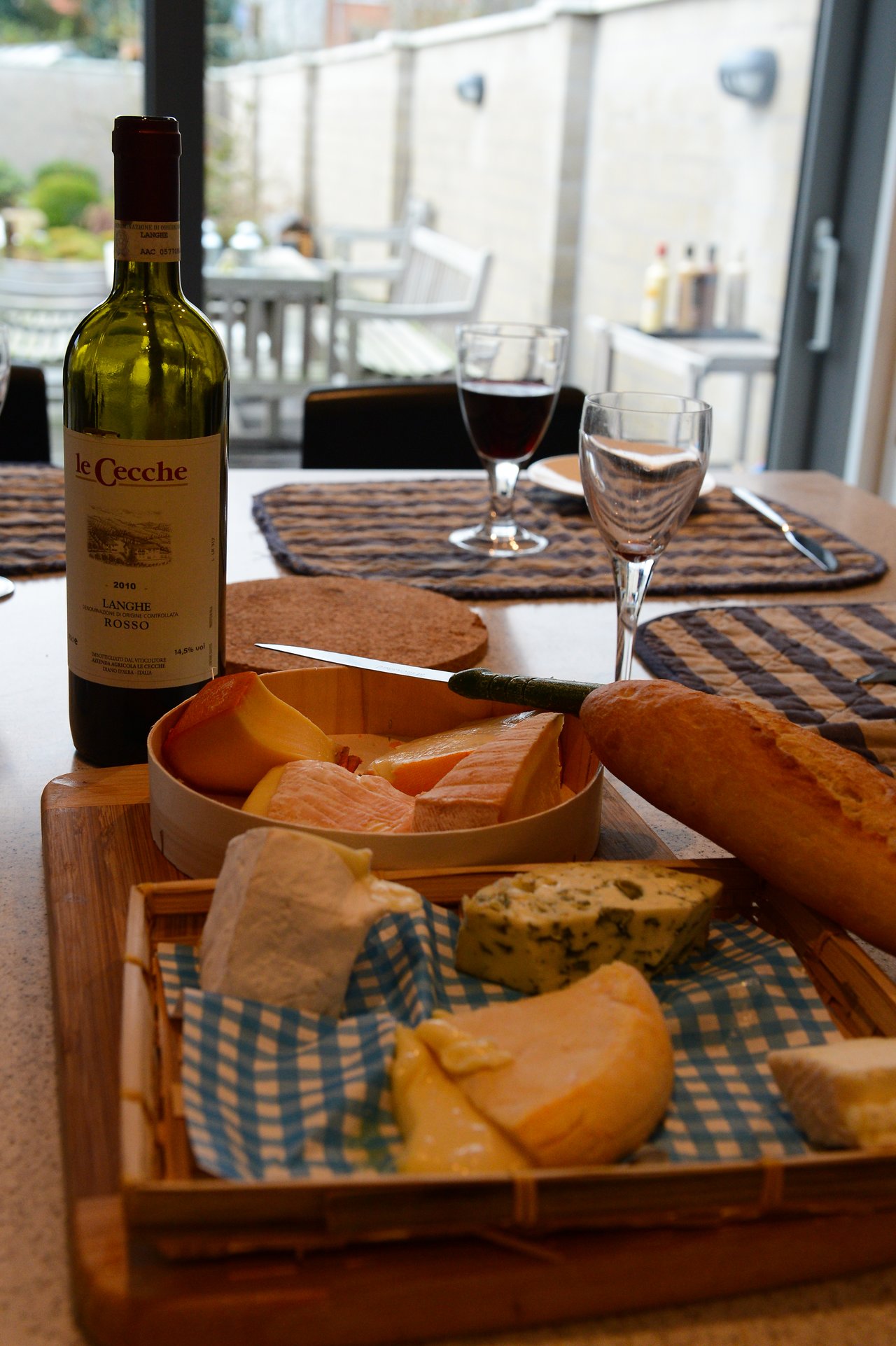 A table set with cheese, bread, and wine, ready for a meal.
