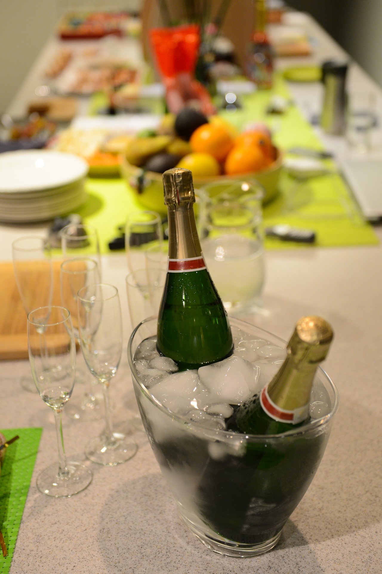 Two bottles of champagne chill in an ice bucket on a table set for Christmas Eve celebration.