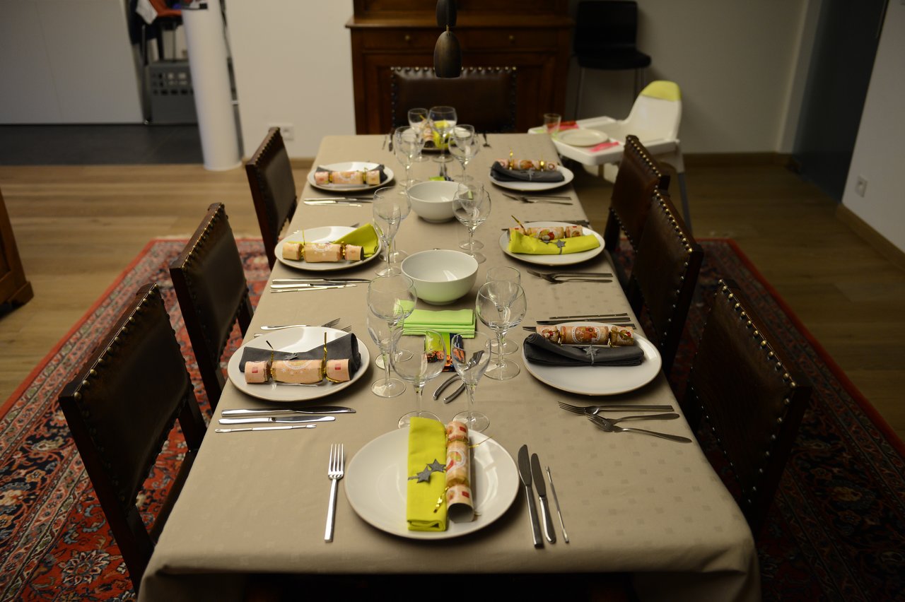 A dining table set for Christmas Eve with plates, napkins, crackers, and wine glasses arranged neatly.