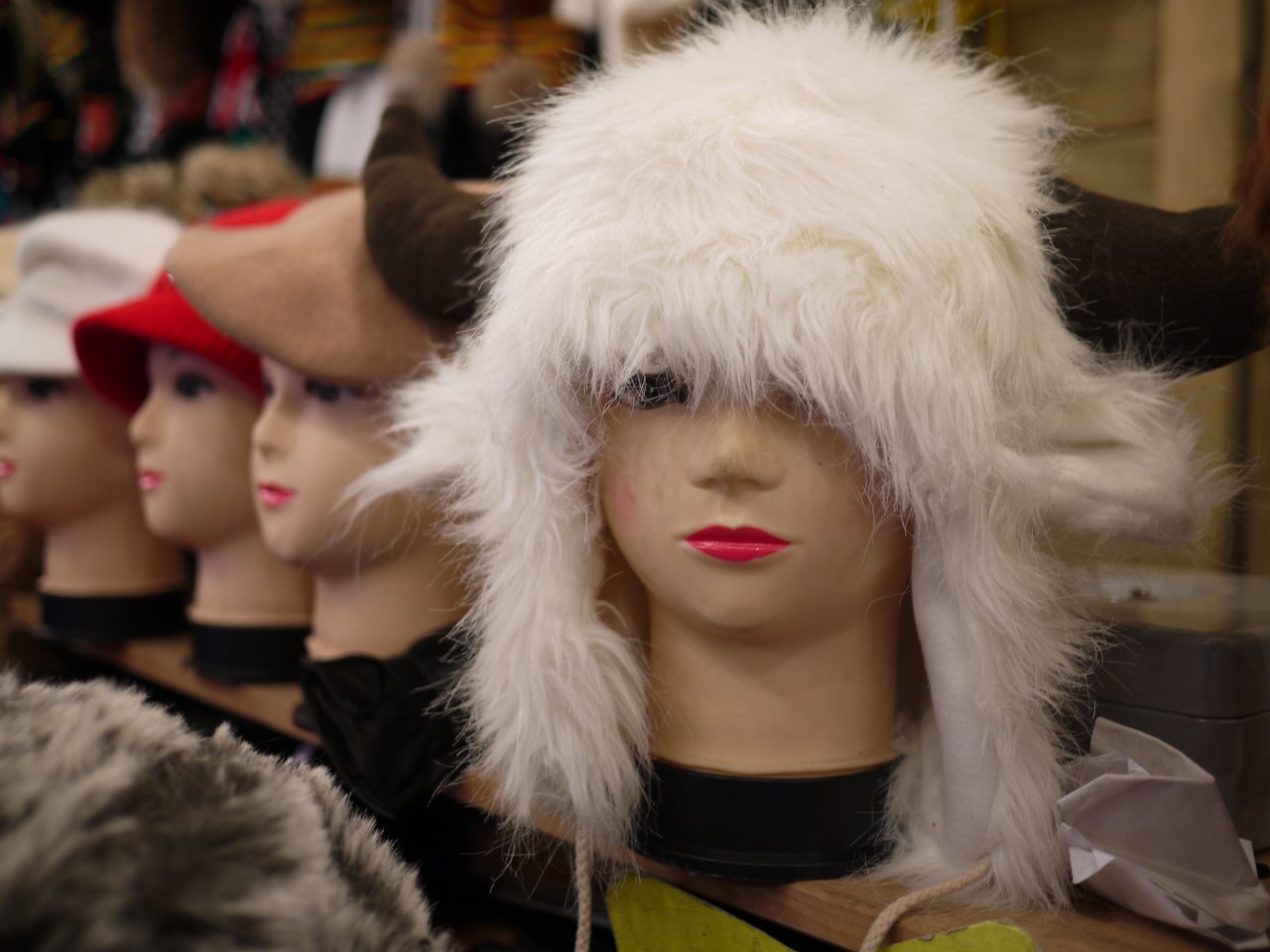 Mannequin heads display various hats, including a fluffy white one with horns, at a Christmas market in Antwerp.