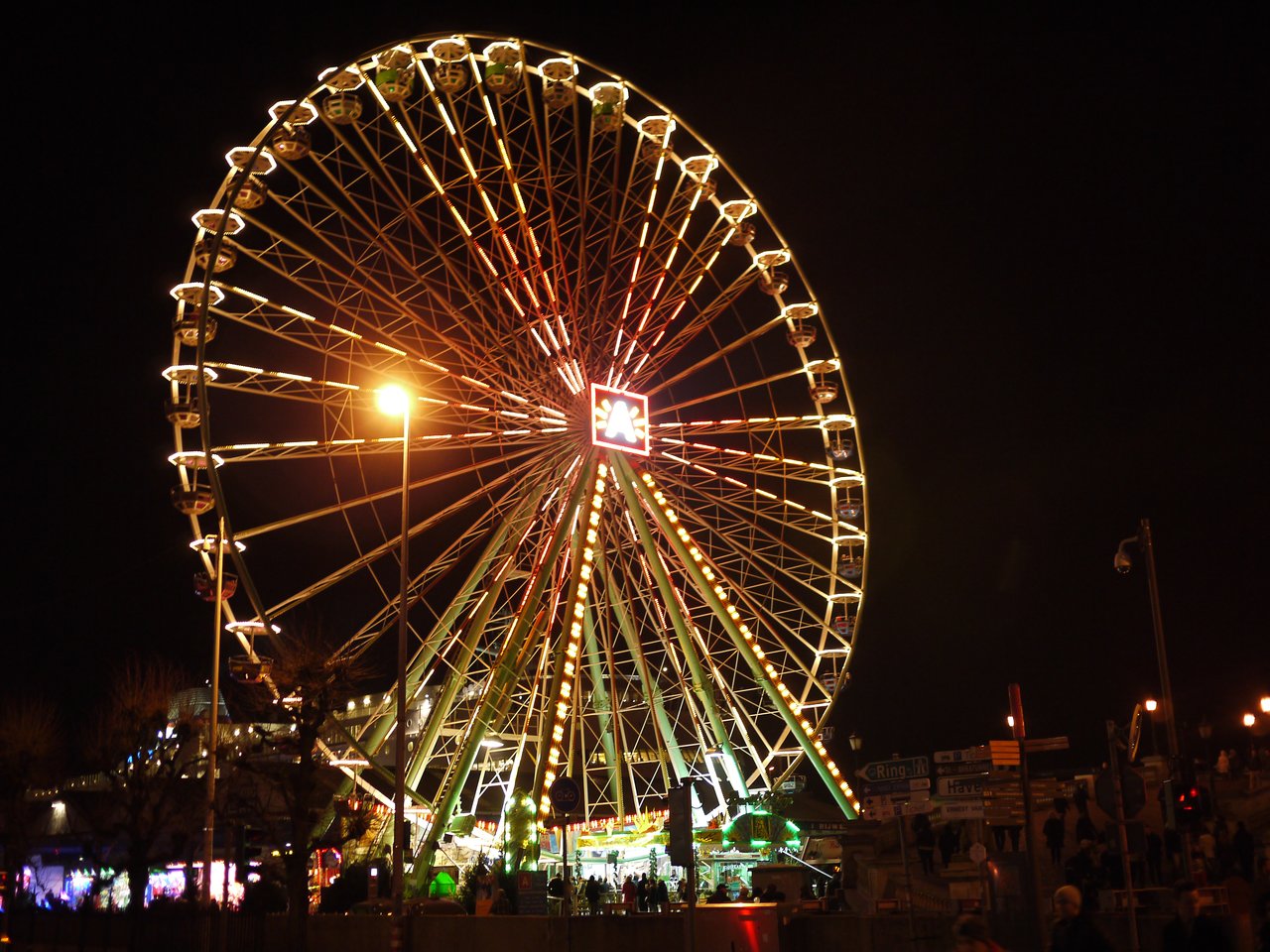 A large Ferris wheel with bright lights at a Christmas market in Antwerp during nighttime.