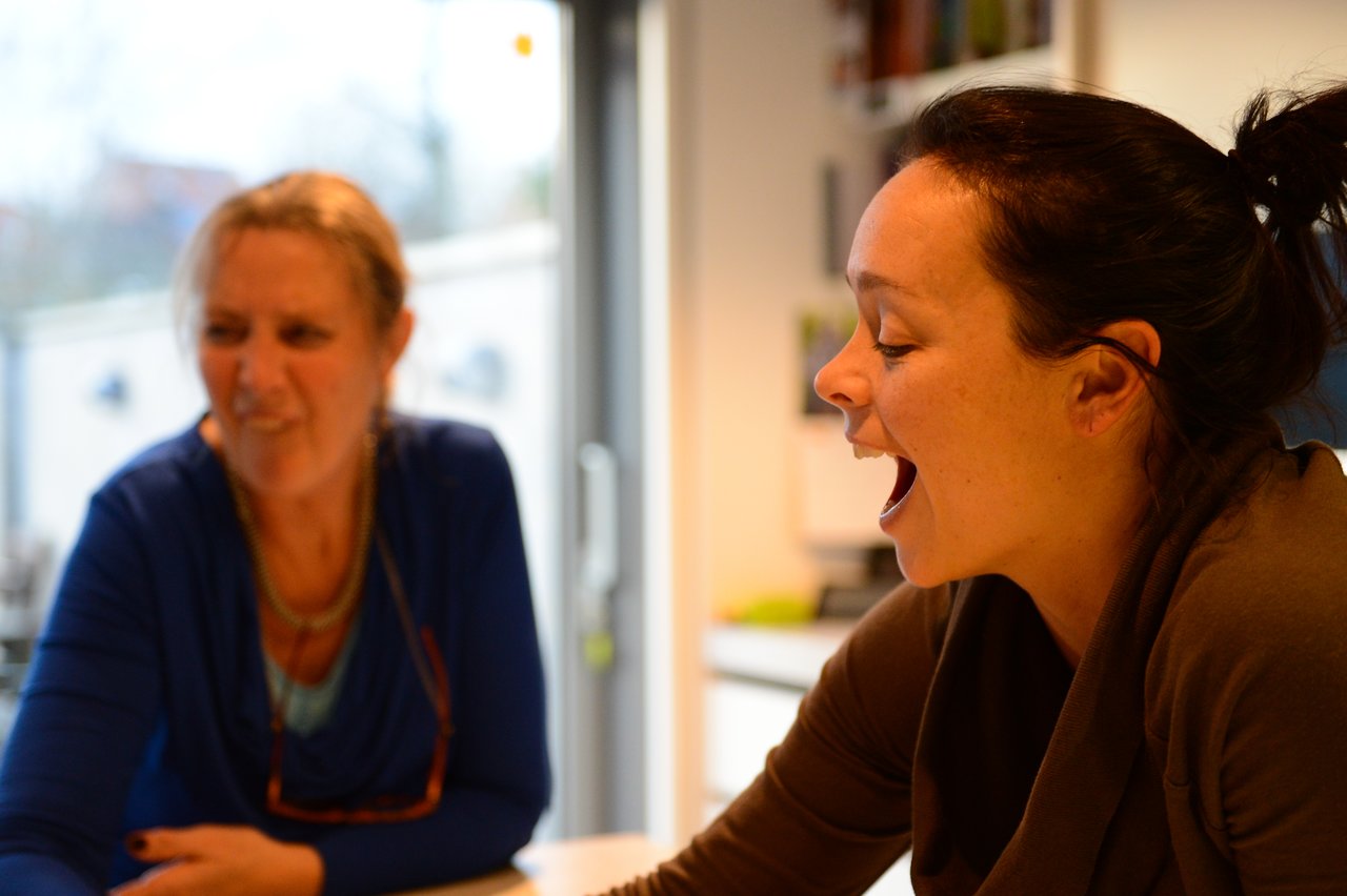 Two people sitting at a table, engaged in a game, reacting with excitement and laughter.