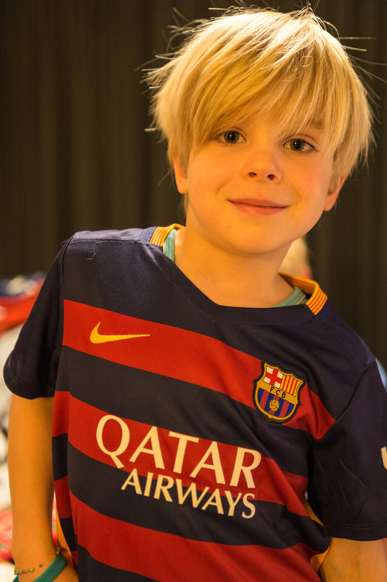 A child wearing a Barcelona soccer jersey smiles at the camera.