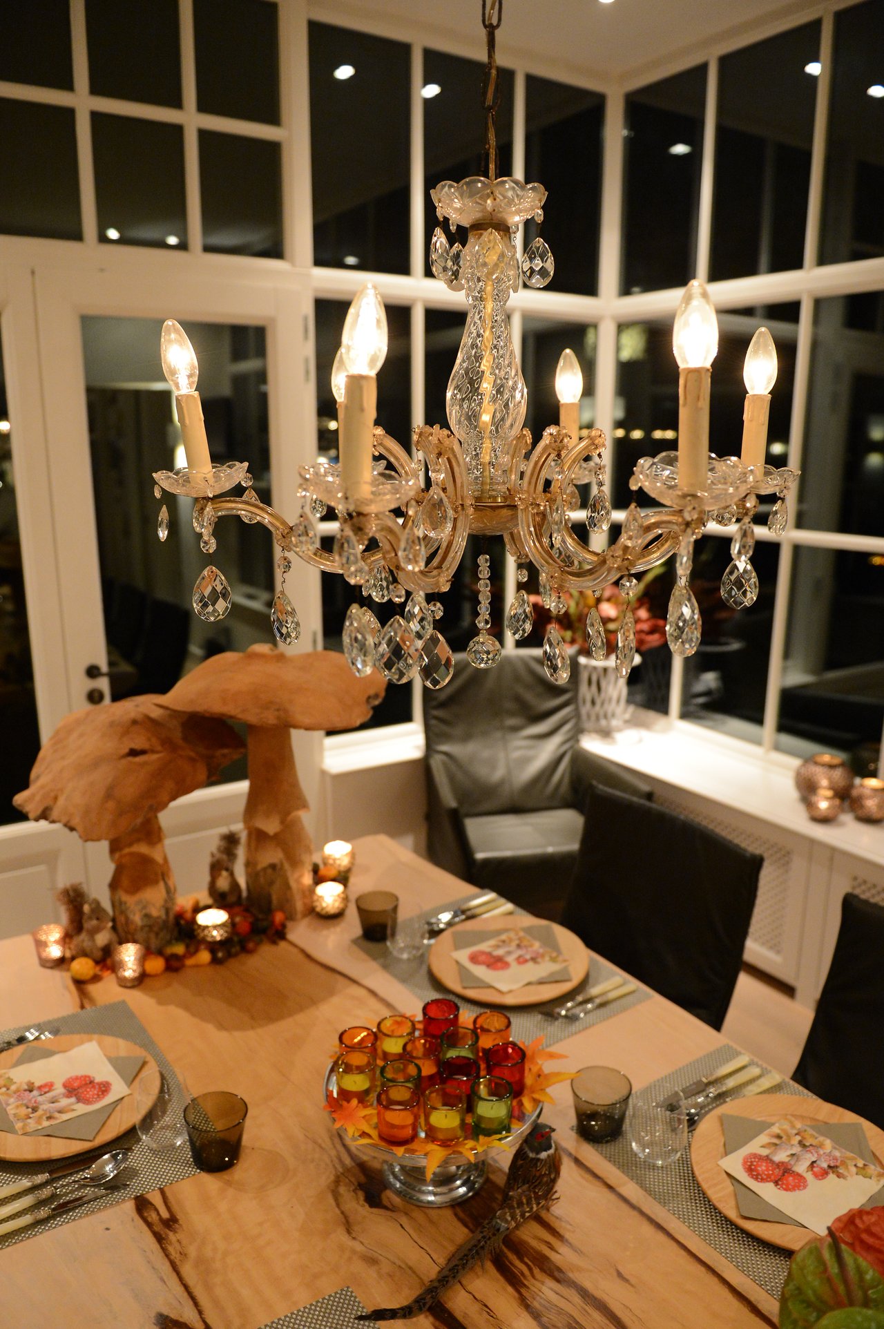 A decorated dining table with plates, glasses, and candles, set for a cooking class in a well-lit room.
