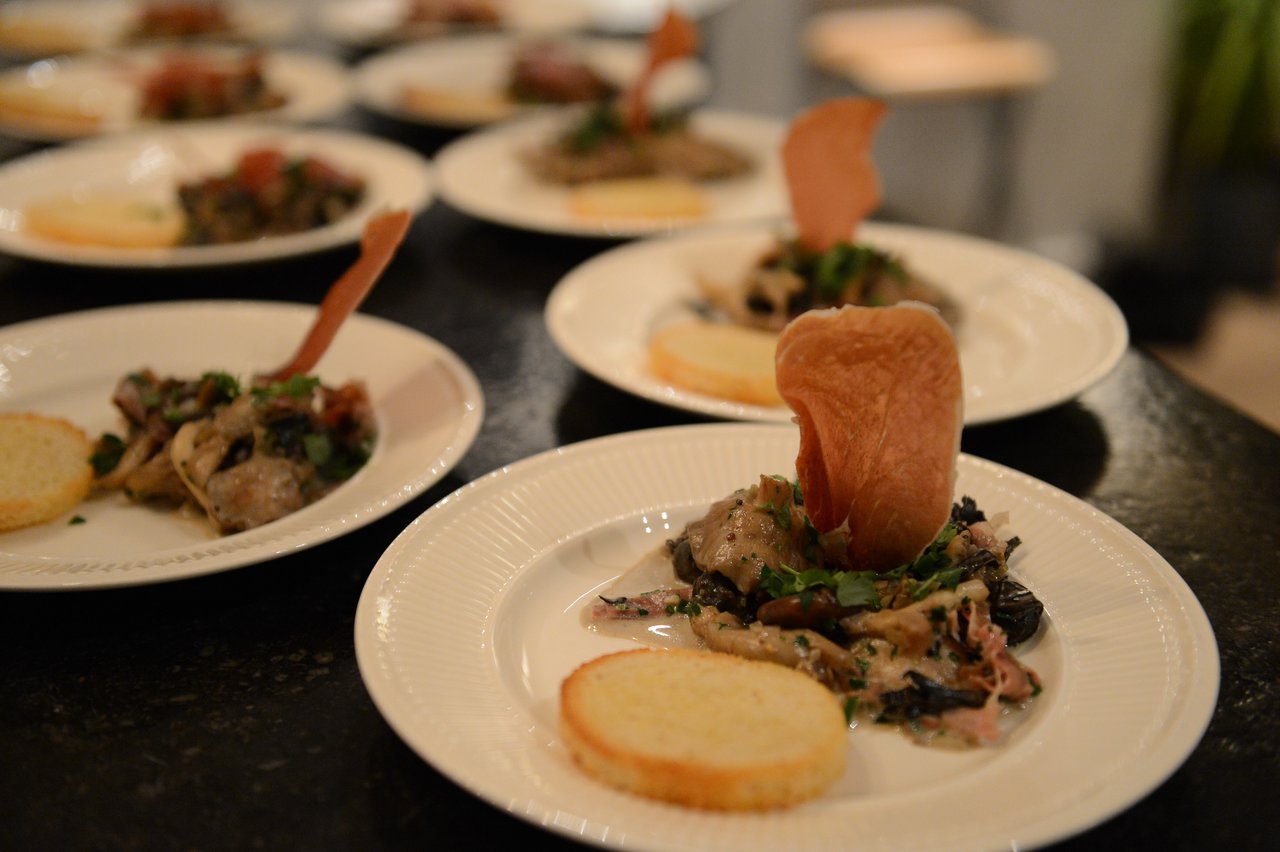 Plates of prepared food with bread and garnishes are arranged on a table during a cooking class.