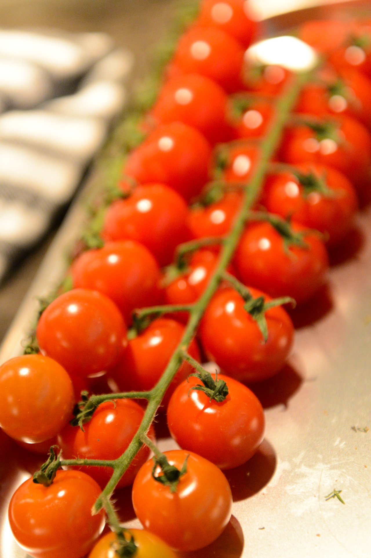 A tray of fresh cherry tomatoes on the vine, prepared for a cooking class.
