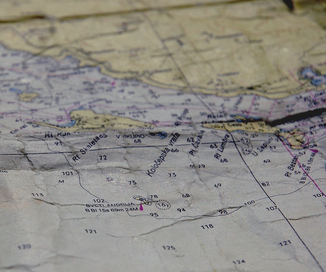 A worn nautical map showing coastal areas, water depths, and navigation markings near Croatia.