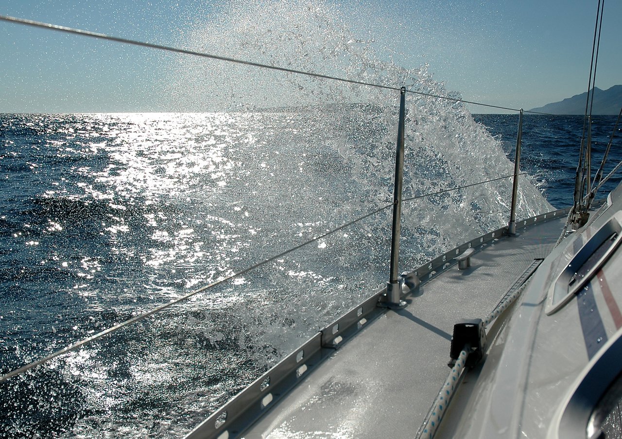 Water splashes against the side of a sailing boat as it moves through the open sea.