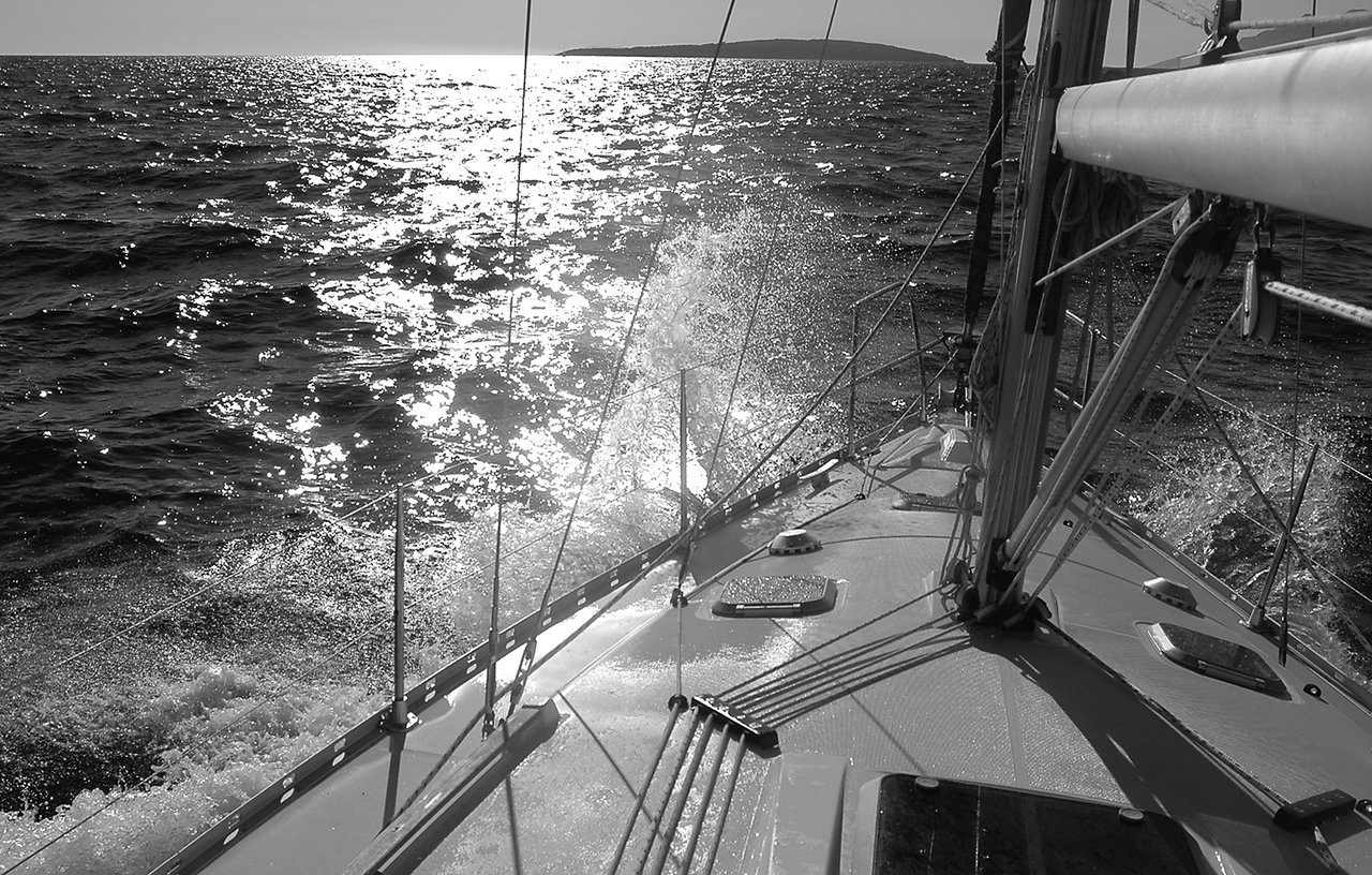 Water splashes against the side of a sailing boat as it moves through the open sea.