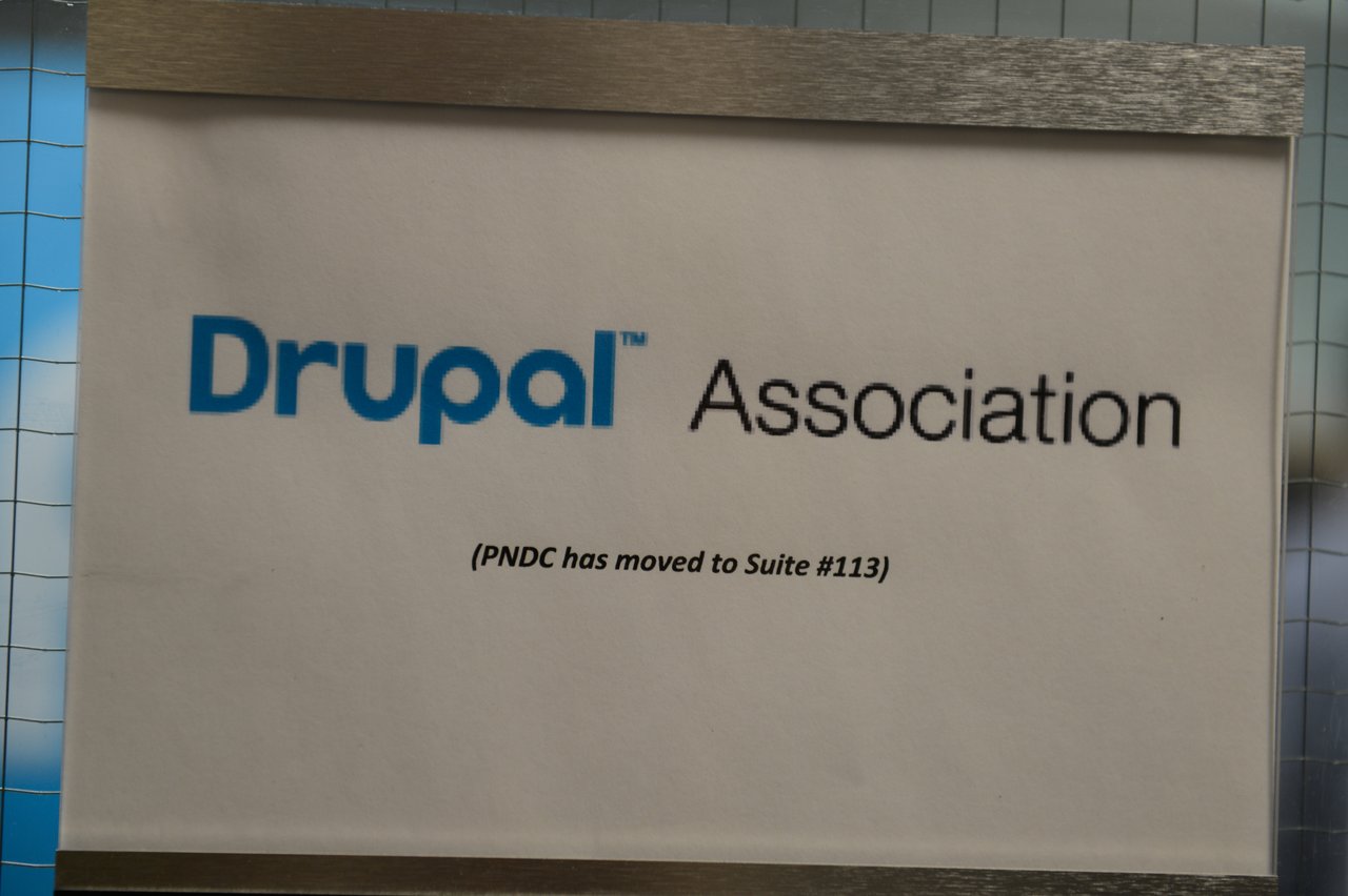 Sign on a door displaying "Drupal Association" with a note indicating that PNDC has moved to Suite #113.