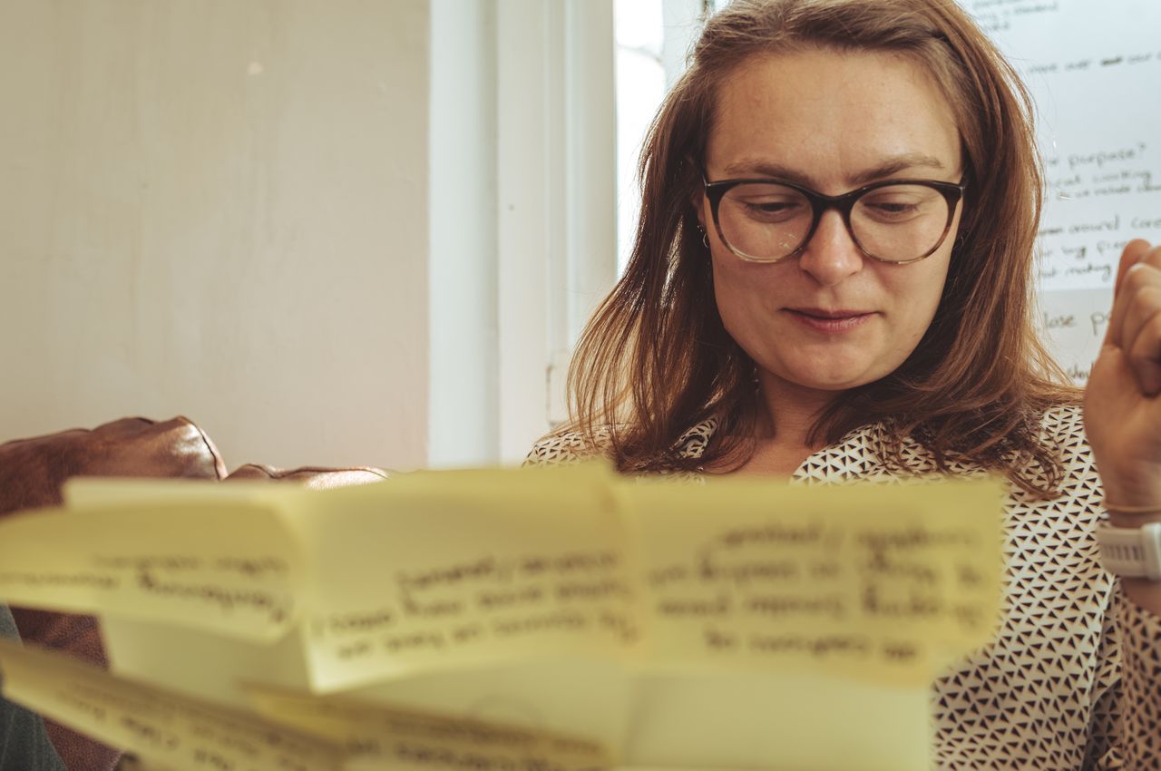 A woman is sitting behind her laptop, which is covered in yellow sticky notes.