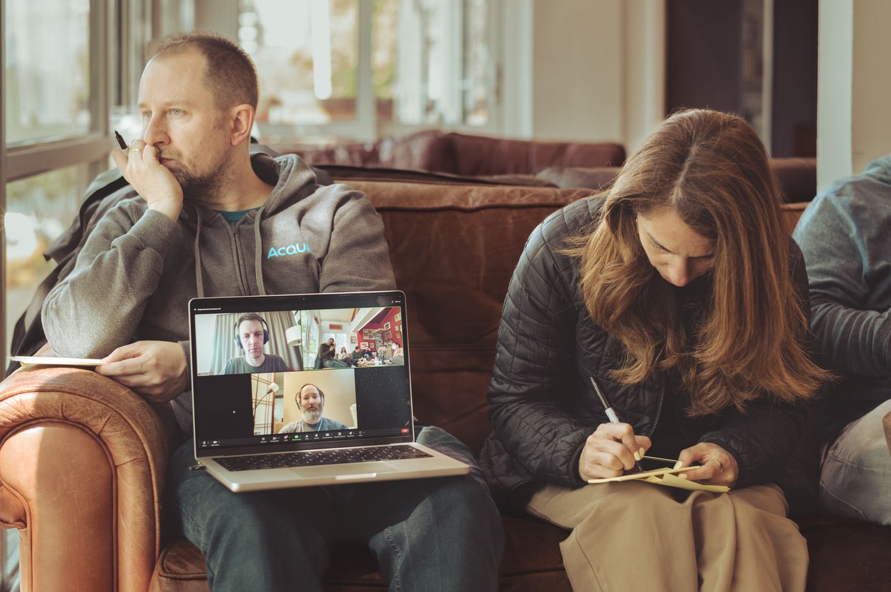 A man with a laptop on his lap, facing towards the room.