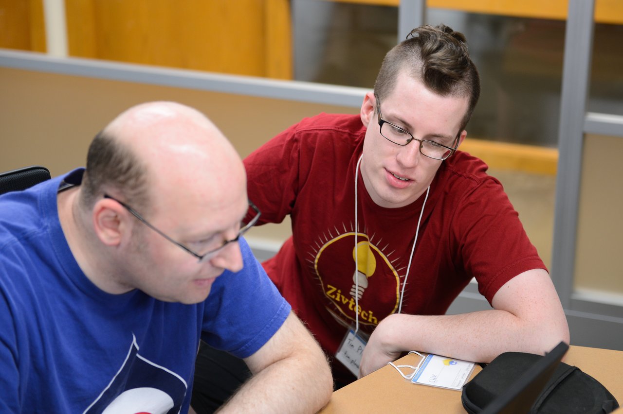Two people collaborating at a table, looking at a laptop screen during a Drupal developer sprint.