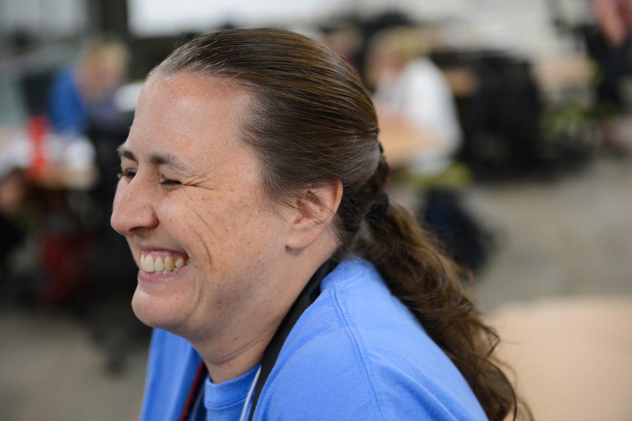A person in a blue shirt smiles and laughs during a Drupal Developer Summit sprint event.