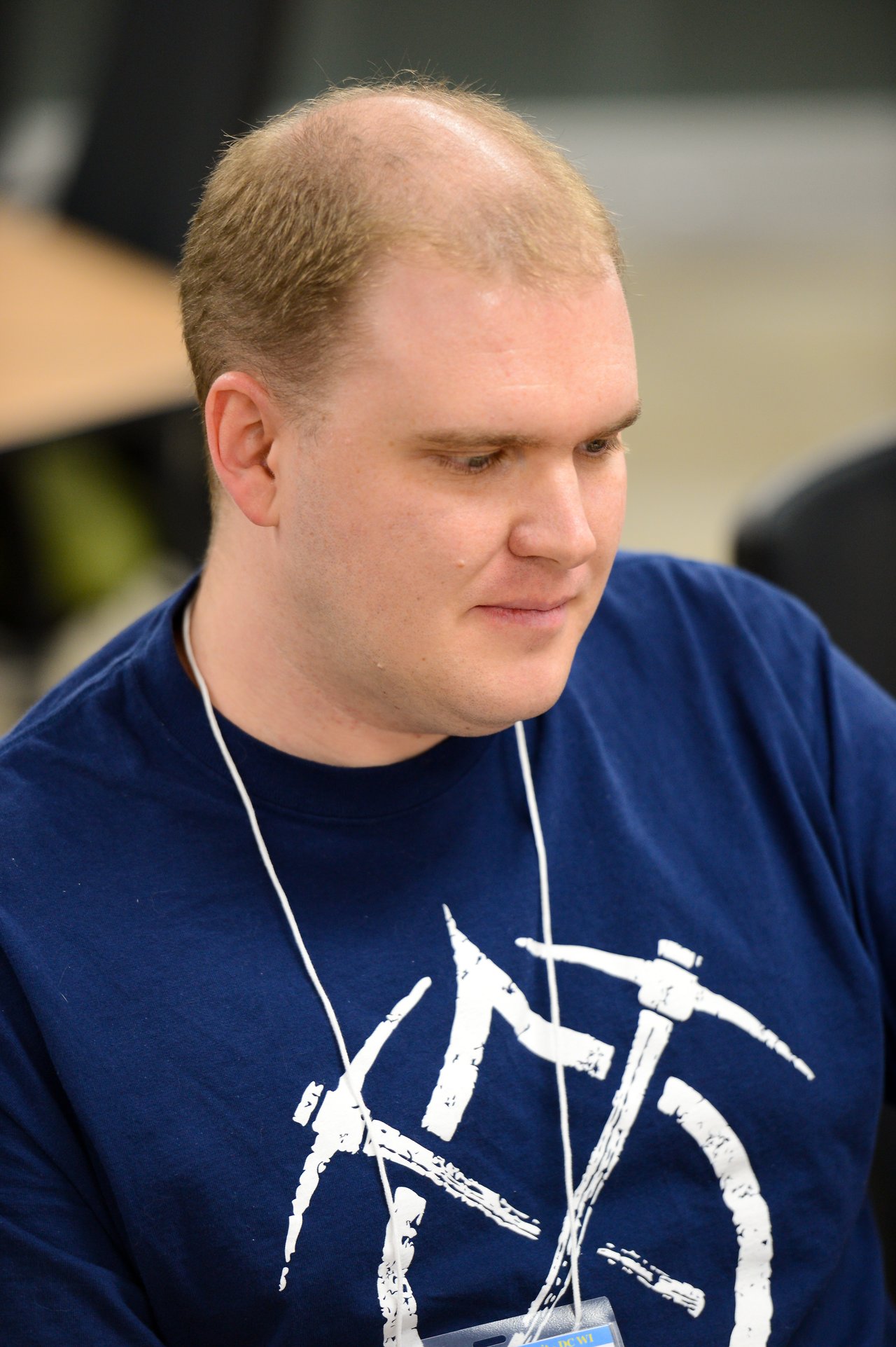 A person wearing a blue t-shirt and a name badge is focused on a task during the Drupal Developer Summit.
