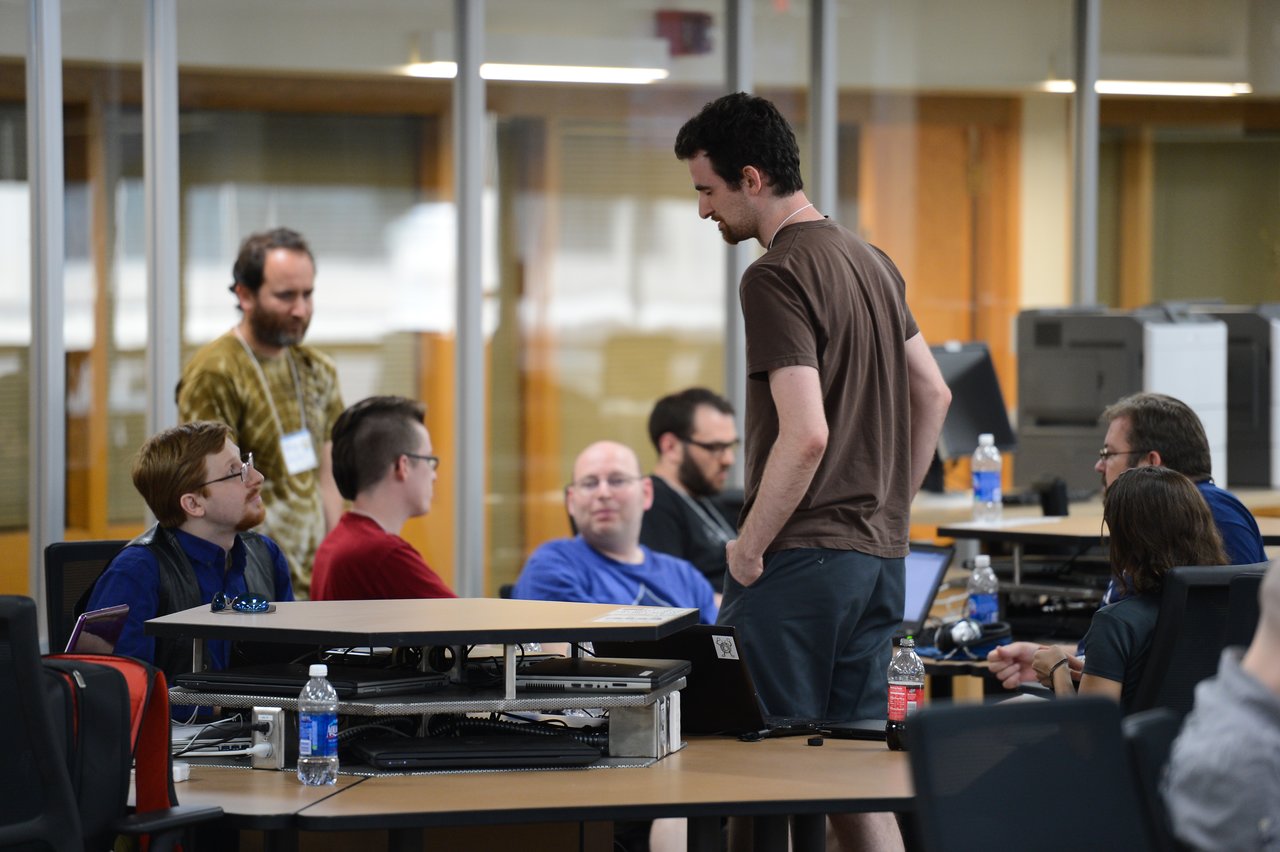 A group of people collaborate at a table with laptops during a Drupal developer sprint.
