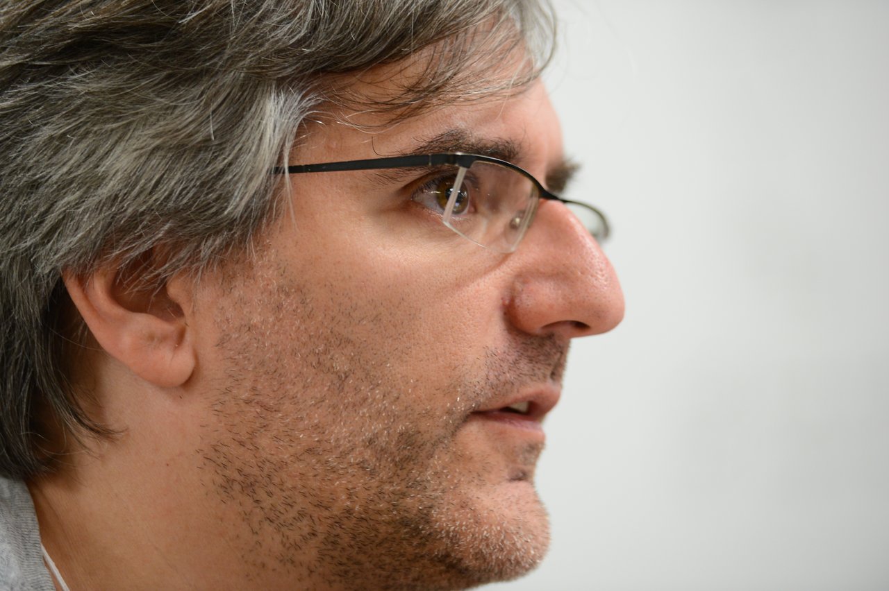 Close-up of a person wearing glasses, attentively listening or speaking during the Drupal Developer Summit sprint.