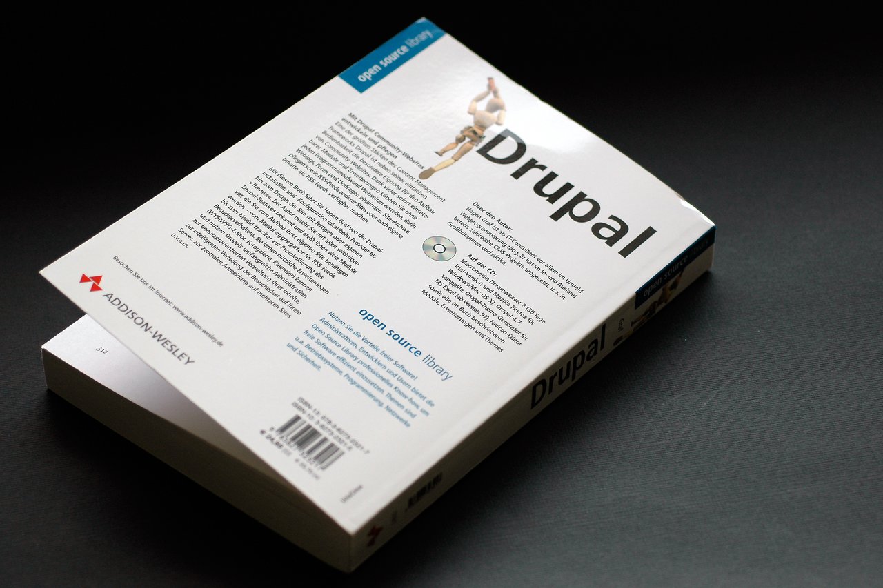 A book titled "Drupal", published by Addison-Wesley, placed on a dark surface with its back cover visible.